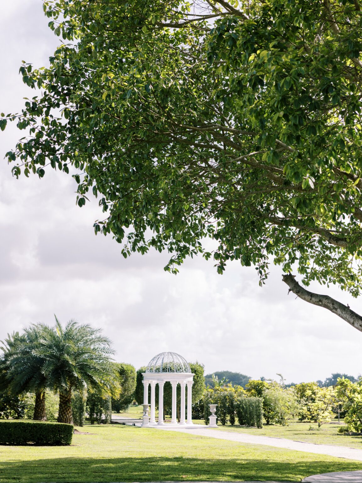 White gazebo framed by oak canopy at Cinco Farm garden wedding venue in Miami