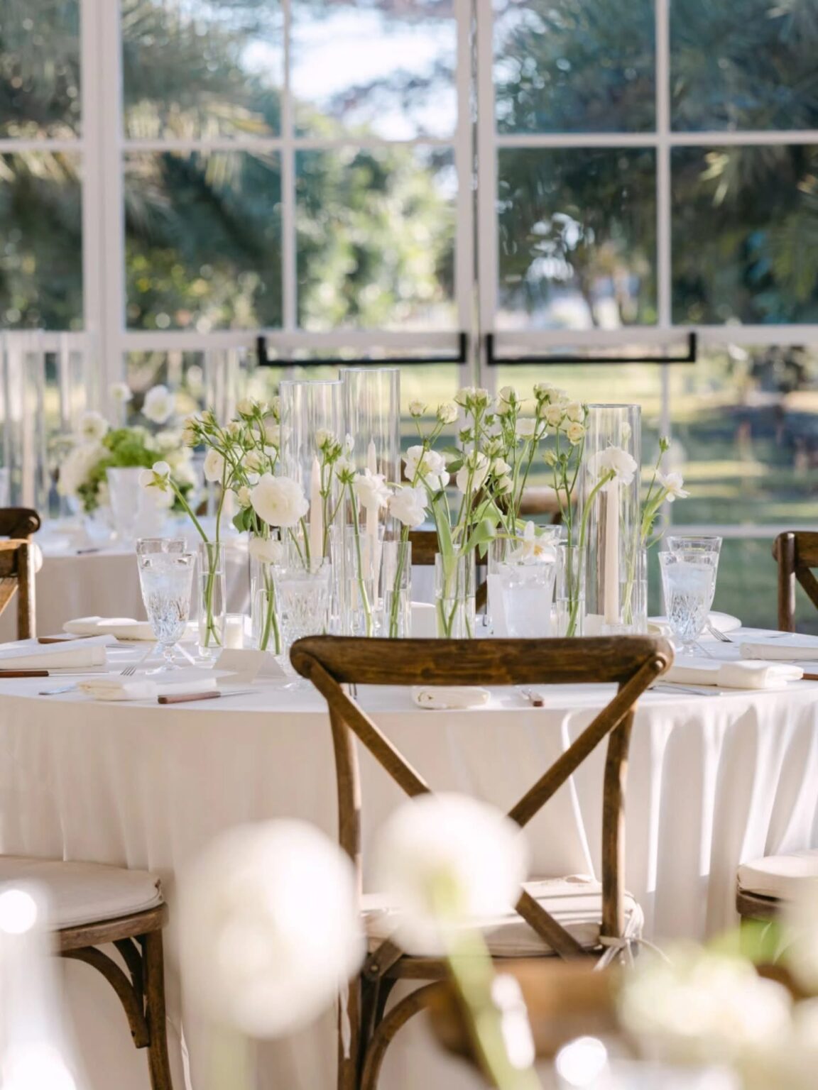 Elegant reception tablescape with white florals in the glasshouse at Cinco Farm Miami